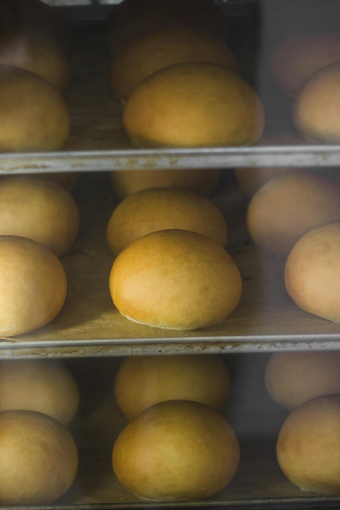 A close-up of golden brown buns baking on trays inside an oven, showcasing their texture and color.