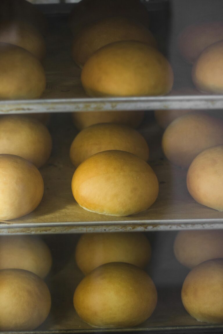 A close-up of golden brown buns baking on trays inside an oven, showcasing their texture and color.